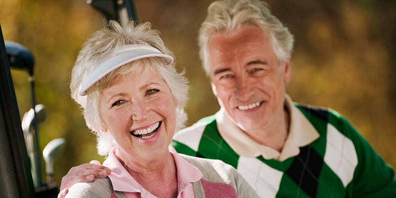 golfers in golf cart on golf course, smiling, portrait
